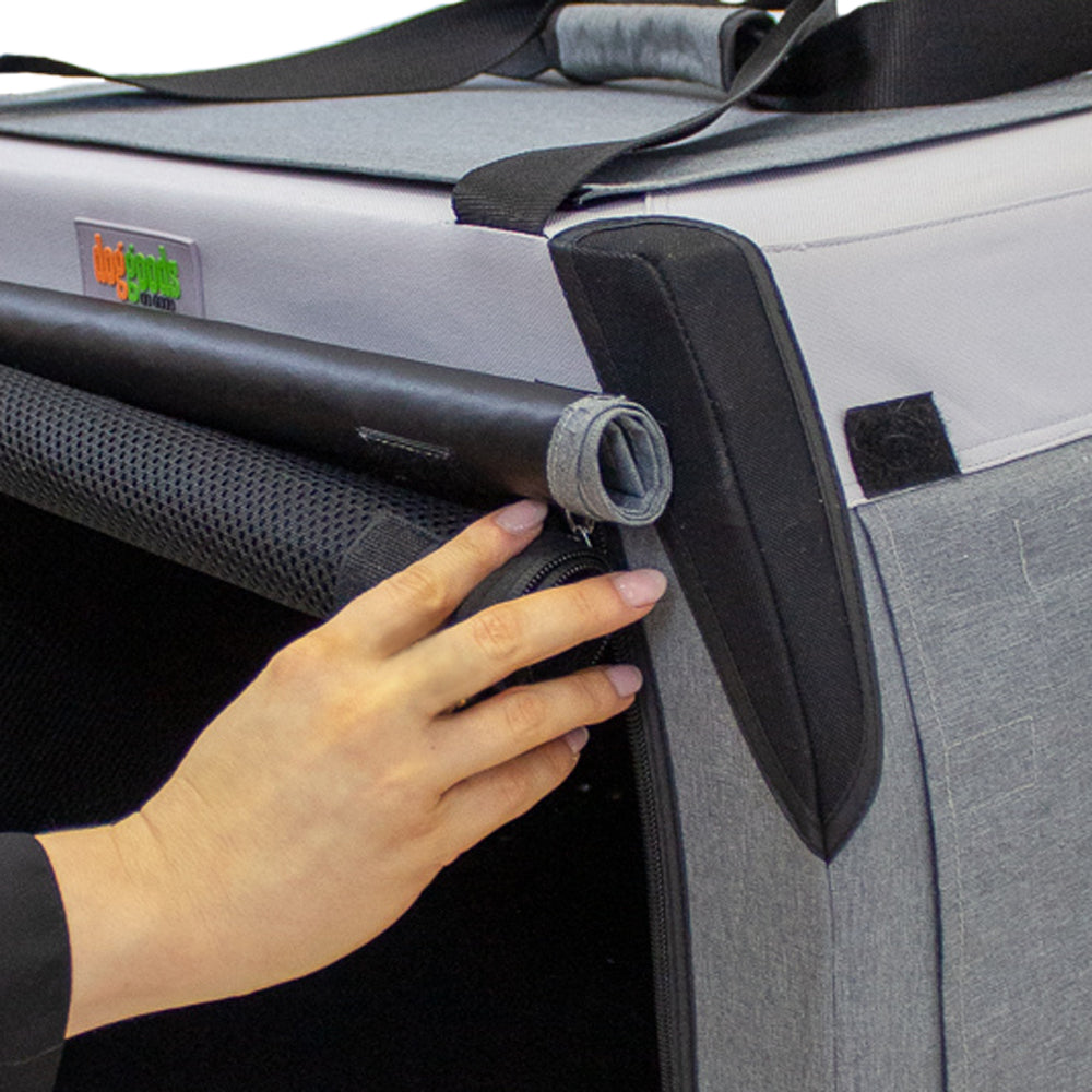 Close-up of a foldable dog crate with a hand rolling up the mesh screen and blackout shade, secured with Velcro for adjustable ventilation and privacy.