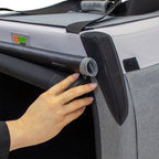 Close-up of a foldable dog crate with a hand rolling up the mesh screen and blackout shade, secured with Velcro for adjustable ventilation and privacy.