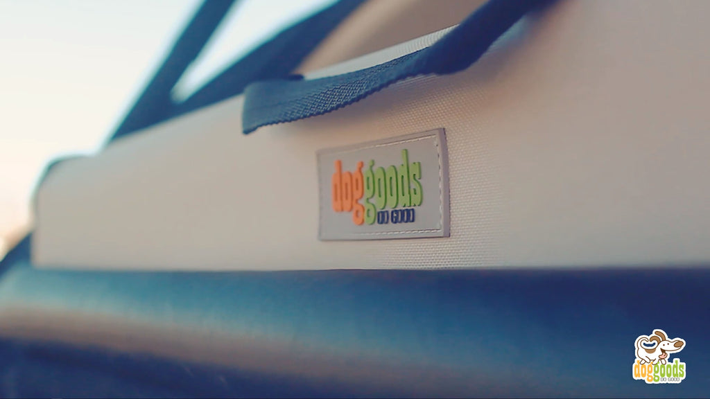 Close-up of the DogGoods logo stitched onto the foldable dog crate. The durable fabric and sturdy handle highlight the brand's quality and design.