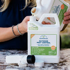 A person pours liquid into a white Wondercide Outdoor Pest Control Concentrate for Yard + Garden container with a detached sprayer and label visible on a marble surface.