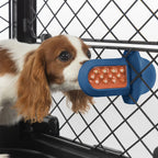 A dog licking a royal blue Groov Training Aid attached to a black dog crate