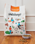 Petaluma dog food bag with a bowl of dog food on a wooden floor