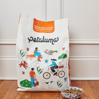 A bag of Petaluma brand dog food with an illustration of a person riding a bicycle with a dog leash attached to the bike, alongside a bowl of dog food.