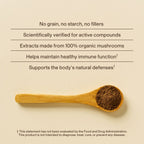 A wooden spoon with organic mushroom powder rests on a beige surface beside text promoting Real Mushrooms' Pet Defenders with Qrill™ Pet—an antioxidant supplement for pets, offering filler-free ingredients and natural immune support (12 units).