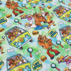 The Dog Bandana - Scooby-Doo™ by Sassy Woof features a colorful pattern with Scooby-Doo characters, the Mystery Machine, hamburgers, dog collars, bones, magnifying glasses, and LIKE WOW text on a blue and green background.