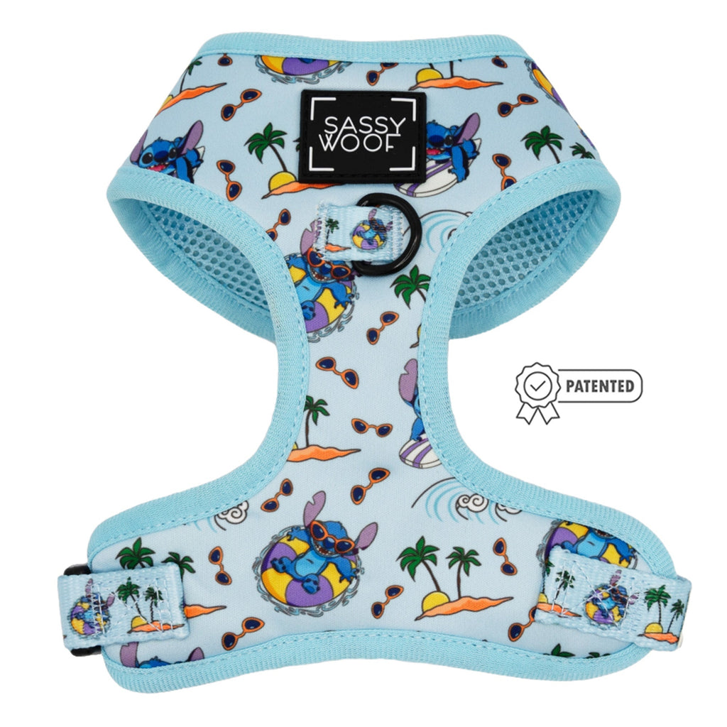 The Dog Adjustable Harness - Disney's Stitch by Sassy Woof features a light blue tropical print with islands, palm trees, waves, and Stitch on pool floats. Includes black Sassy Woof logo patch and PATENTED badge. Perfect for your puppy’s growth plan.