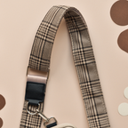 Black plaid Cocopup London dog walking bag strap with metal clasps, displayed on overlapping paper circles.