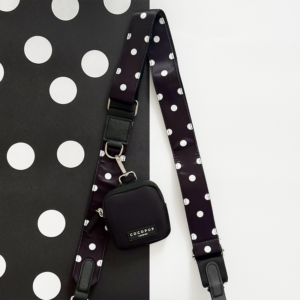 Cocopup London black bag and small treat pouch on a black and white polka dot surface.