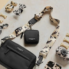 Black Cocopup London dog walking bag with a cow-print strap, matching treat pouch, phone case, and poop bag dispenser.