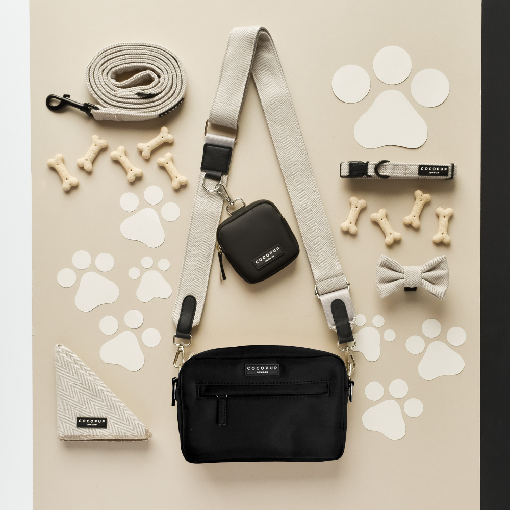 Black Cocopup London dog walking bag with matching black leash, collar, bow tie, bandana and assorted treats.