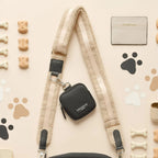 Black Cocopup London dog walking bag, dog treats, cream card holder, and paw prints on a beige background.