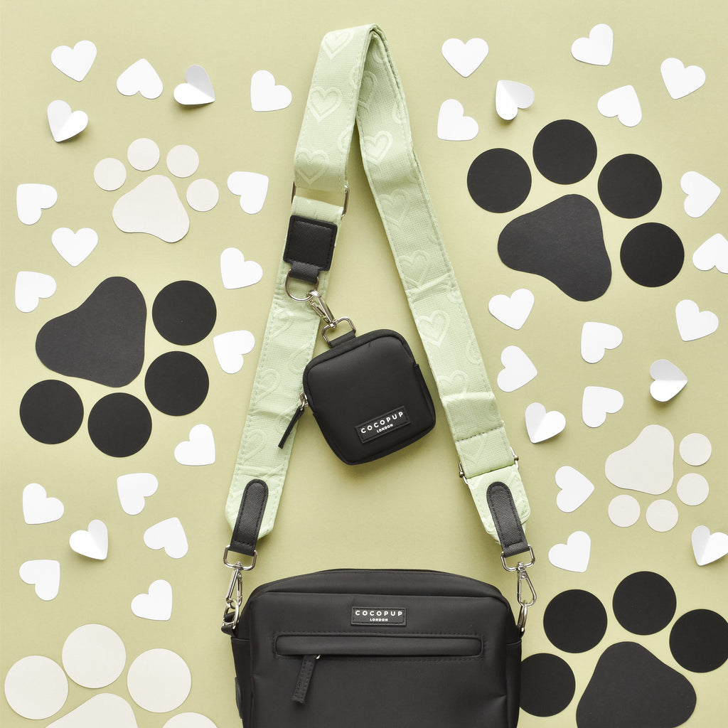 Black Cocopup London dog walking bag with mint strap, paper heart accents, and attached poop bag dispenser.