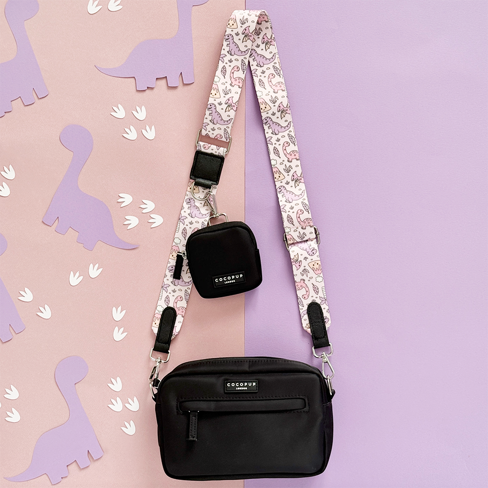 Black Cocopup London dog walking bag with pink strap featuring dinosaur pattern.