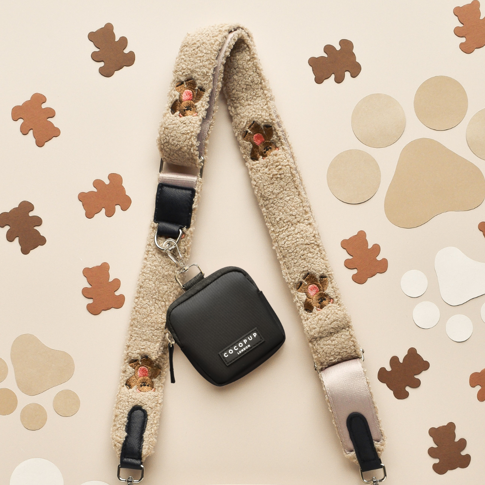 Black dog walking bag with beige faux fur paw strap, bone patterns, and matching treat pouch from Cocopup London.
