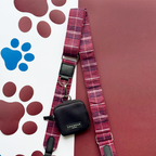 Black Cocopup London dog walking bag with maroon plaid leash on a paw print background.