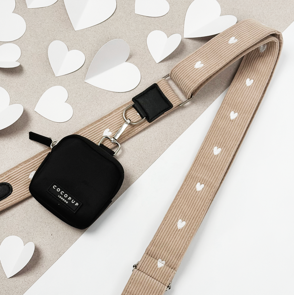 Beige dog walking bag strap with white heart pattern, displayed on scattered paper heart shapes.