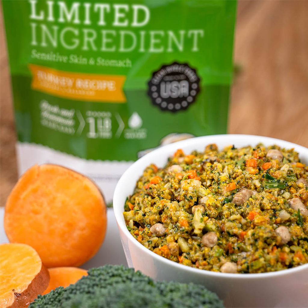 Limited Ingredient Turkey Recipe dog food in a bowl with sweet potato and broccoli beside green USA bag