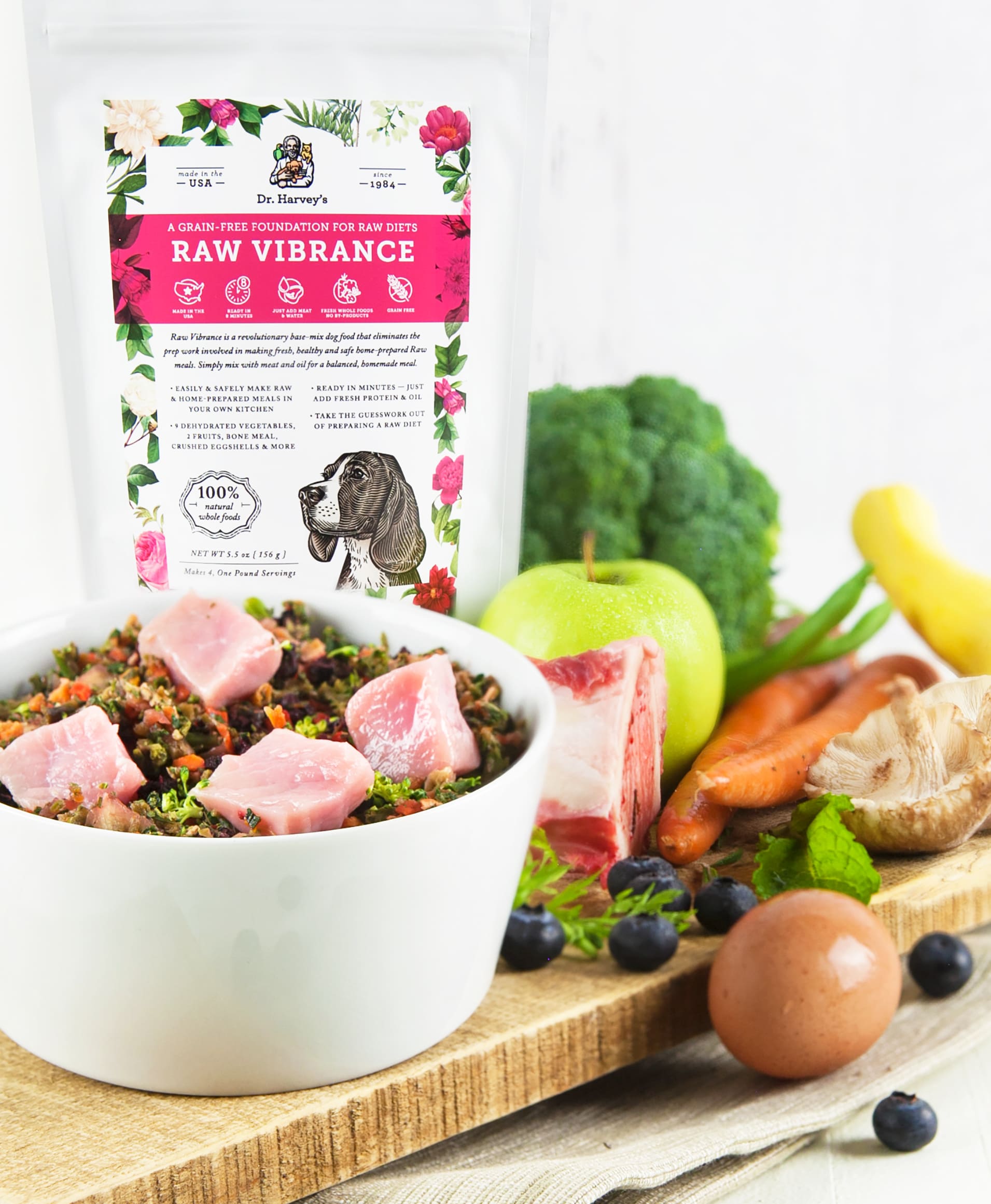 Dr. Harvey's Raw Vibrance grain-free dog food mix bag with bowl of raw meat, vegetables, blueberries, apple, egg, and bone.