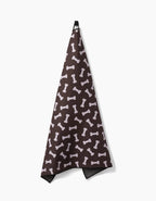 The Geometry Sweet Treats towel, made from highly absorbent recycled materials, features a playful dog bone pattern and hangs from a black loop against a white background.