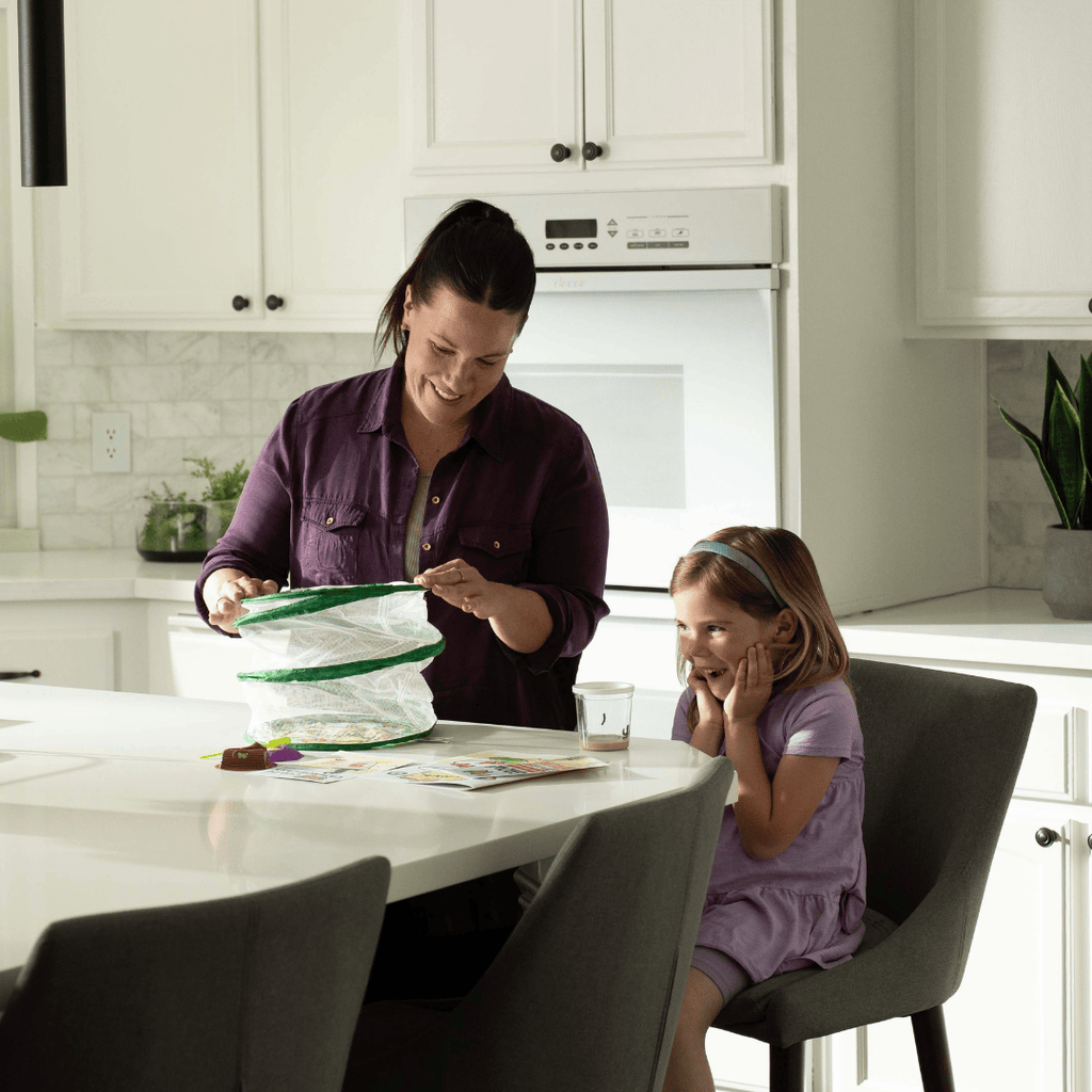 Woman and child in a kitchen setting up the mesh butterfly habitat.