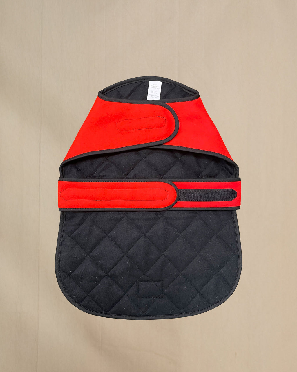 Blaze orange dog coat with quilted lining on a beige background