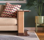 A Cat-e-Corner table placed next to a sofa, integrating a cat's scratching post with a small table, in a room with a plant and a colorful cushion.