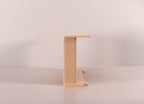 A Cat-e-Corner table placed next to a sofa, integrating a cat's scratching post with a small table, in a room with a plant and a colorful cushion.