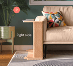 A Cat-e-Corner table placed next to a sofa, integrating a cat's scratching post with a small table, in a room with a plant and a colorful cushion.