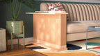 A Cat-e-Corner table placed next to a sofa, integrating a cat's scratching post with a small table, in a room with a plant and a colorful cushion.