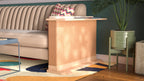 A Cat-e-Corner table placed next to a sofa, integrating a cat's scratching post with a small table, in a room with a plant and a colorful cushion.