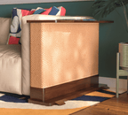 A Cat-e-Corner table placed next to a sofa, integrating a cat's scratching post with a small table, in a room with a plant and a colorful cushion.