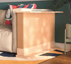 A Cat-e-Corner table placed next to a sofa, integrating a cat's scratching post with a small table, in a room with a plant and a colorful cushion.