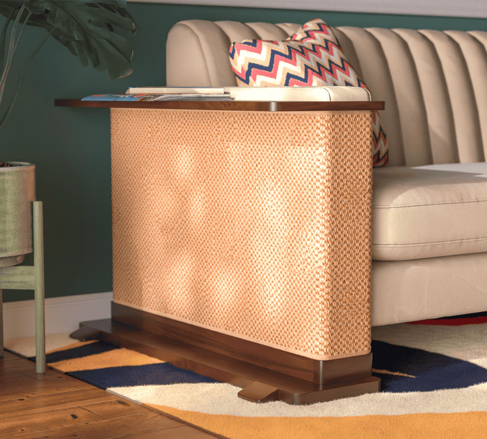 A Cat-e-Corner table placed next to a sofa, integrating a cat's scratching post with a small table, in a room with a plant and a colorful cushion.