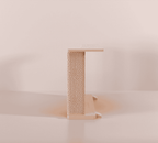 A Cat-e-Corner table placed next to a sofa, integrating a cat's scratching post with a small table, in a room with a plant and a colorful cushion.