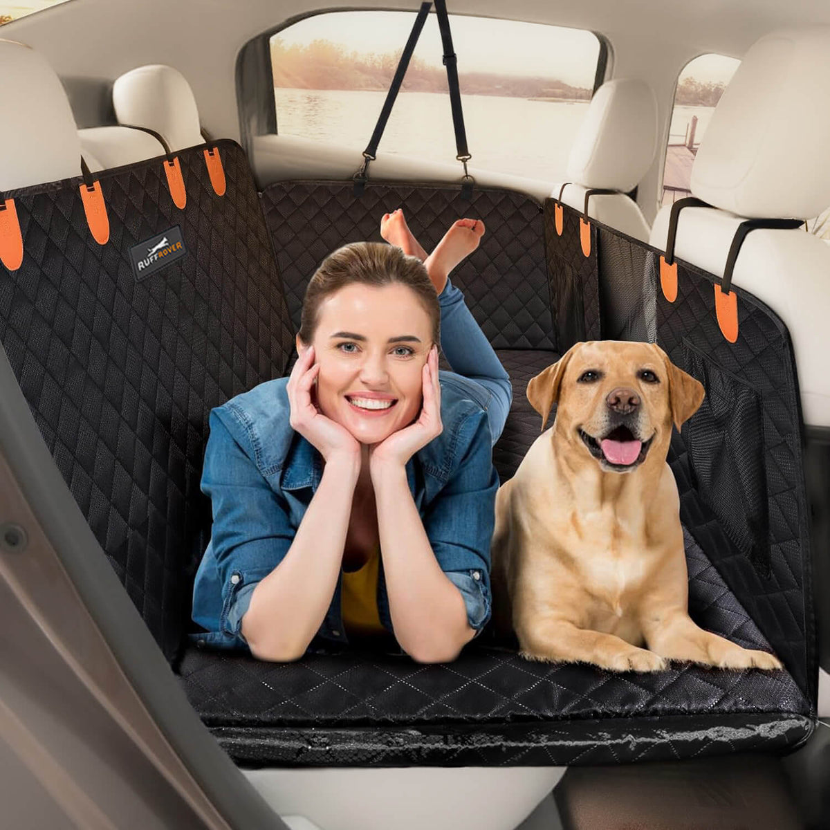RuffRover 2.0 hard bottom dog car seat protector in black, with a woman and a dog lying on it in a vehicle.