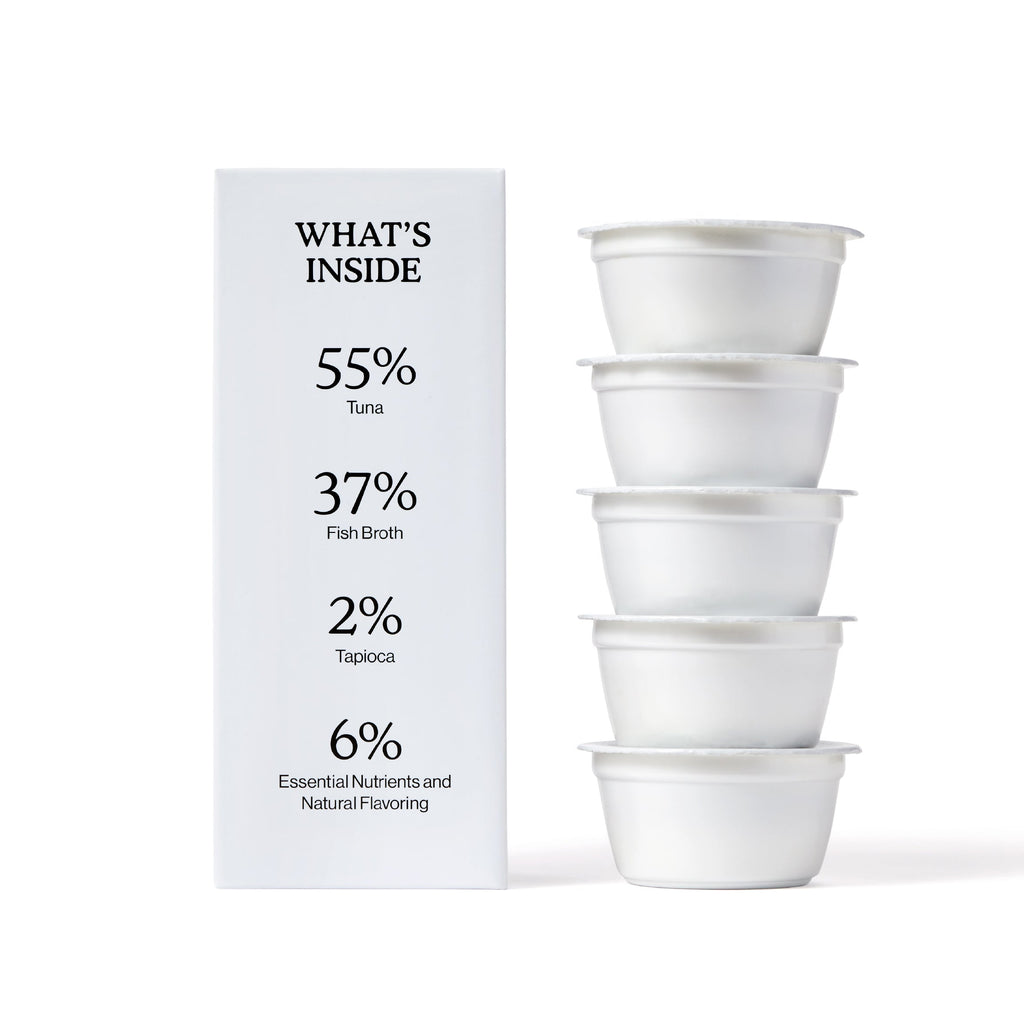 A box labeled WHATS INSIDE lists ingredients and percentages beside four stacked white cups, featuring Cat Person Tuna Shreds in Broth: 55% tuna, 37% fish broth, 2% tapioca, 6% nutrients and natural flavoring for balanced nutrition.