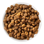 A white bowl filled with round, brown Cat Person Duck & Turkey Dry Food kibble pieces, viewed from above on a white background.