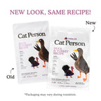 Two packages of Cat Person Duck & Turkey Dry Food are shown side by side; the original packaging is on the left, and the new packaging featuring updated graphics and branding is on the right.