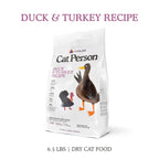 A 6.5 lb white bag of Cat Person Duck & Turkey Dry Food features illustrated duck and turkey on the front, along with nutrition info, making it a healthy, grain-free dry cat food for your feline.