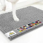 Angled view of Muddy Mat® Anti-Mud Dog Door Mat showcasing dense chenille nubs in light grey with dog’s paws on white floor