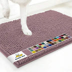 Angled top view of plum Muddy Mat® anti-mud dog door mat showing dense chenille microfiber surface and a dog paw on a white floor