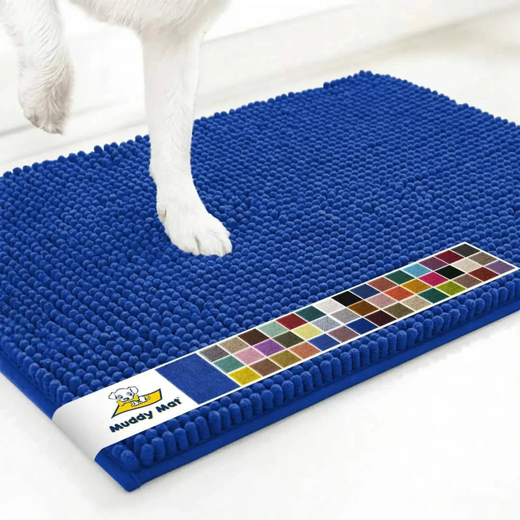 Top-angle view of Muddy Mat anti-mud dog door mat, royal blue, showing chenille noodle surface, non-slip edge, and a dog’s paw on white floor