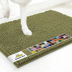 Close-up top view of Muddy Mat anti-mud dog door mat sage showcasing dense chenille nubs with white floor and a dog’s paw for scale